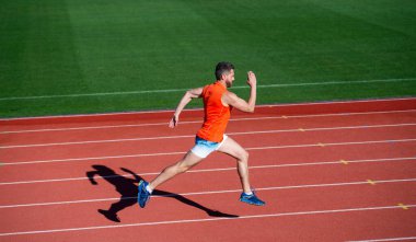 Açık stadyumdaki hipodromda koşan enerjik atletik kaslı adam koşucu, yarışma