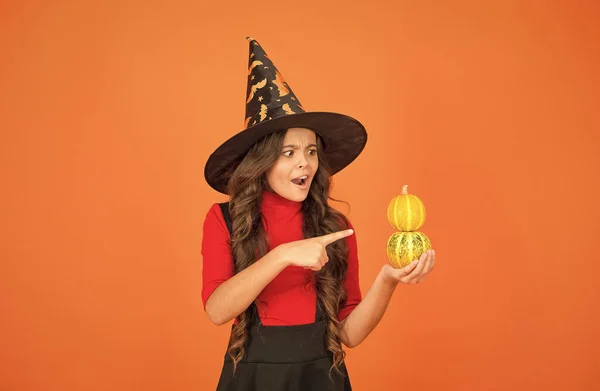 Happy halloween party kid wearing witch cosplay costume and having fun while celebrating autumn traditional holiday pointing finger on pumpkin, halloween jack o lantern — Stock Photo, Image