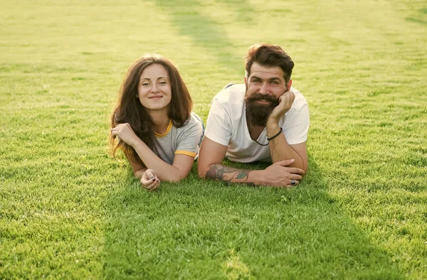 Беззаботная пара, наслаждающаяся солнечным днем, отдыхающая на зеленом лугу, концепция летних каникул — стоковое фото
