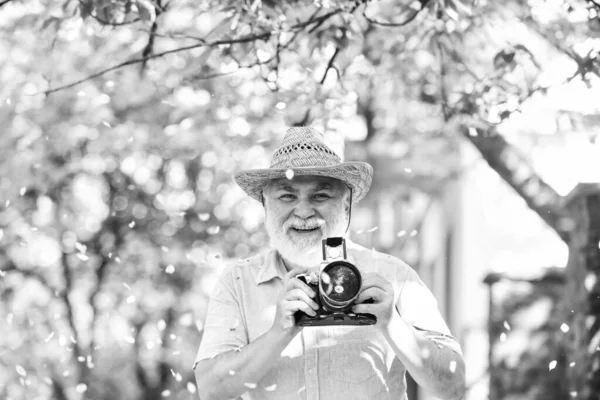 En sevdiği sokakta yürüyor. Boş zamanın tadını çıkarıyorum. Seyahat ve turizm. Seyahat fotoğrafı. Çiçek açan bahçede fotoğrafçı. Çekici güzellik. Kıdemli adam kamerayı tut. Emeklilik gezisi. Bahar tatili — Stok fotoğraf