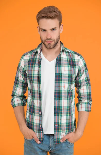 Stunning confidence. Beauty standards. Masculine outfits. Stylish guy in fashionable clothing. Handsome man in checkered shirt and jeans. Regular clothing student yellow background. Casual clothing