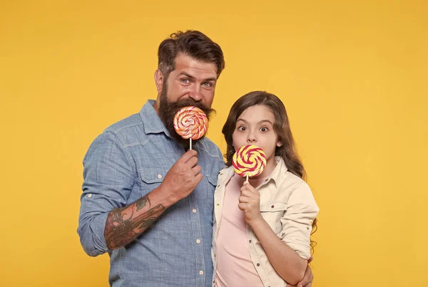 Gelukkig familie vader en dochter eten lolly gele achtergrond, zelfgemaakte karamel concept — Stockfoto