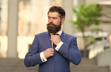 Ceketli, kravatlı, dışarıda yürüyen olgun bir adam. Ofise giderken. Modern yaşam tarzı. Mavi takım elbiseli iş adamı kravat bağlıyor. Adam düğün ceketi giyiyor. Şehrin kendine güvenen avukatı. Kendi isteğimle asiyim