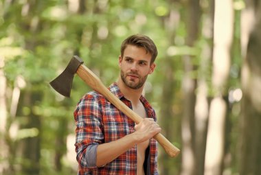 Yakışıklı ve kaslı oduncu elinde baltayla kamp yapıyor.