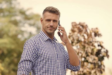 Telefon için beklemedeyim. Yakışıklı bir adam dışarıyı arıyor. Cevap ver. Gelen arama. Telefon görüşmesi. Mobil iletişim. Yeni teknoloji. Modern hayat