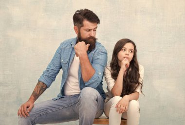 Ne olmak istiyorsan onu ol ve ne istersen onu giy. Sakallı adam, küçük çocuğa bak. Baba ve kızı tabureye oturur. Moda kıyafeti. Sıradan bir tarz. Moda trendleri. Moda tarzı. Kuaför salonu. Berber Dükkanı