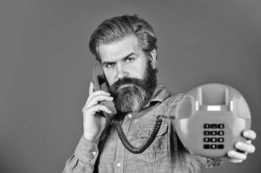 Olgun sakallı adam retro telefonda konuşuyor. Modern yaşamda klasik teknoloji. Genç adam telefonda konuşuyor. Son sınıf hipster 'ı eski telefonu gösteriyor. Telefonu olan acımasız bir adam.