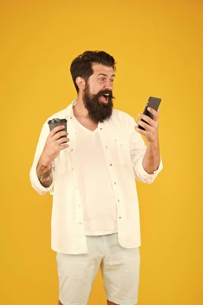 Spänning. Det moderna livet. Glad kille med mustasch och skägg dricker kaffe. läsa meddelande på smartphone. mogen skäggig man chattar på telefon och dricker kaffe. morgondryck i pappersmugg — Stockfoto