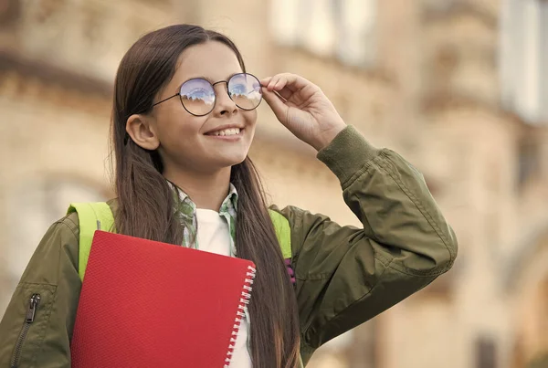Szczęśliwy dzieciak naprawić okulary, aby zobaczyć lepiej trzymając książkę szkolną jesień na zewnątrz, wzrok — Zdjęcie stockowe
