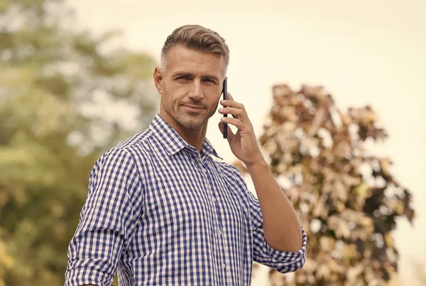 Telefon için beklemedeyim. Yakışıklı bir adam dışarıyı arıyor. Cevap ver. Gelen arama. Telefon görüşmesi. Mobil iletişim. Yeni teknoloji. Modern hayat