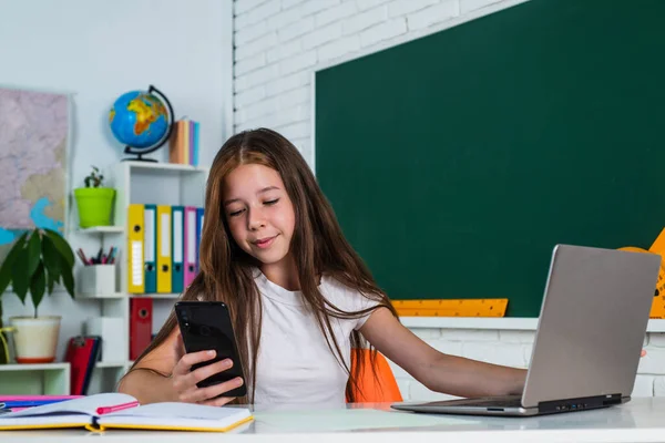 Χαμογελαστός έφηβος κορίτσι κάνει selfie στο smartphone στον υπολογιστή στην τάξη του σχολείου, σύγχρονη ζωή — Φωτογραφία Αρχείου