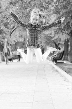 Yorulmak bilmez ve enerjik bir aktivite. Küçük bir çocuk fiziksel aktivite için normal bir şekilde atlıyor. Aktif çocuk yaz parkında oyun oynamaktan zevk alıyor. Çocukken açık hava aktivitesi için giyinmiş küçük bir çocuk.