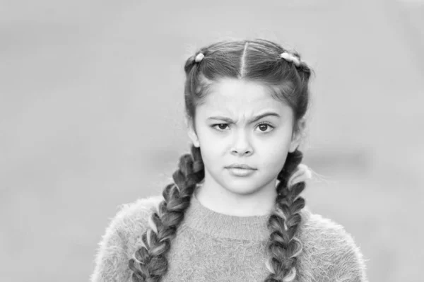 ¿Qué pasa? Niña con mirada desconcertada. Los niños pequeños usan largas trenzas morenas. Niño adorable en el estilo de moda casual. Linda niña al aire libre. Infancia. Día internacional de los niños —  Fotos de Stock