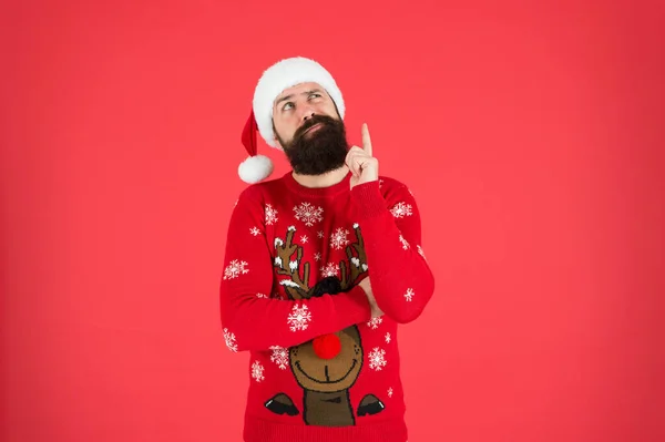 Winter fashion. Guy wearing winter clothes accessory. Bearded Santa claus red background. Something on his mind. Winter holidays. Man bearded hipster wear winter knitted hat. Barbershop facial hair — Stock Photo, Image