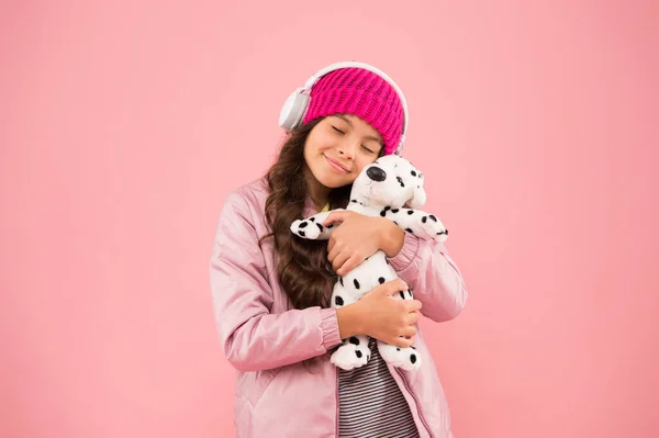 너무 많이 사랑해. 강아지 인형 놀이하는 행복 한 소녀. 핑크 색은 가장 좋아 하는 색이다. 어린 아이는 음악 헤드폰을 듣습니다. 아기가 곱슬머리를 하고 있다. 아늑 한 겨울 시즌이다. 애완 동물 관리. 추운 날씨를 위한 따뜻 한 옷 — 스톡 사진