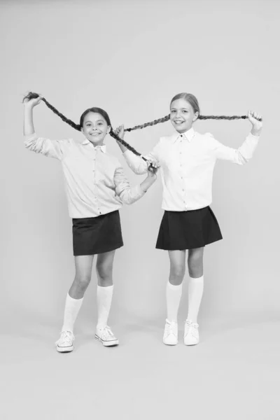 Está na hora de relaxar. meninas felizes em uniforme escolar. meninas inteligentes no fundo amarelo. moda infantil. Amizade e irmandade. Dia do conhecimento. felicidade infantil. conceito de educação. voltar para a escola — Fotografia de Stock