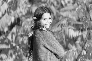 Daha çok oyna, mutlu ol. Sonbahar manzarasında gülümseyen küçük bir çocuk. Küçük kız saçına sonbahar yaprakları takıyor. Mutlu sonbahar tatilleri.