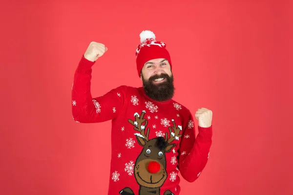 Christmas Deals start. mature hipster beard in knitted sweater. get warm in cold season. winter clothes fashion. festive holiday atmosphere. portrait of happy santa man. bearded man in hat red wall — Stock Photo, Image