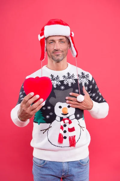 Gift with love. sexy man santa earflap hat. man funny sweater red wall. warm your heart in winter. male share his heart. man ready for xmas party holiday. christmas is here. my new year gift for you — Stock Photo, Image