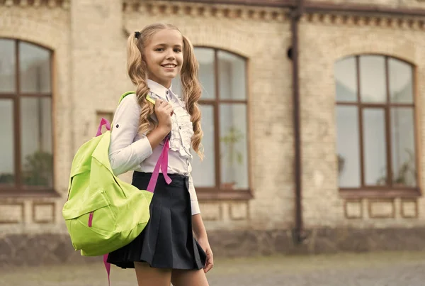 Piccola ragazza portare lo zaino. Felice di essere qui. ricordi d'infanzia felici. sulla strada per la lezione. Torniamo a scuola. studio dei bambini nel parco. rilassarsi su erba verde con sacchetto della scuola. concetto di istruzione. Prima i bambini — Foto Stock