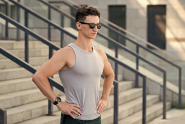 Motive olmuş güneş gözlüklü genç sporcu sabah koşusu için stadyumda hazır.