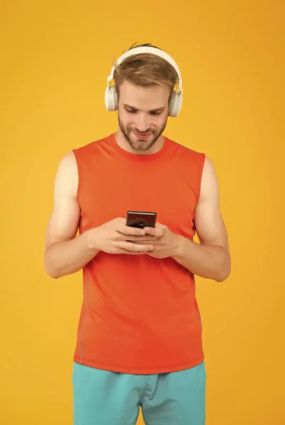 Glad skäggig man lyssna musik i digitala hörlurar med hjälp av mobiltelefon app bär sportiga kläder för träning, sociala nätverk — Stockfoto