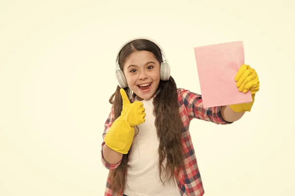 Fröhlicher Reinigungssonntag. Musik hören, während Sie im Haushalt arbeiten. Machen Sie den Haushalt freudiger. Kinder haben Spaß. Putzen macht Sorgen. Putzmittel. kleine Mädchen Kopfhörer in gelben Gummihandschuhen — Stockfoto