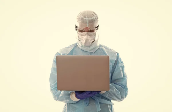 Man läkare epidemiolog bär respirator mask och säkerhet skyddsdräkt under coronavirus pandemi utbrott distans arbetar på datorn, online hjälp. — Stockfoto