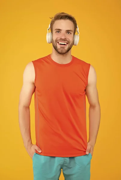 Χαρούμενος νεαρός αθλητής στην αθλητική ένδυση και ακουστικά ακούσετε μουσική κατά την άσκηση, τη φυσική κατάσταση και τη μουσική — Φωτογραφία Αρχείου