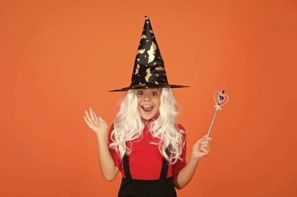 Счастливая девушка надевает парик, держа в руках волшебную шапку, чтобы создать волшебство на Хэллоуин, счастливое чудо на Хэллоуин — стоковое фото
