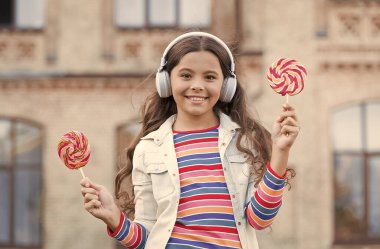 Neşeli kız modern kablosuz kulaklıklar şeker yer, tatlı çocukluk konsepti