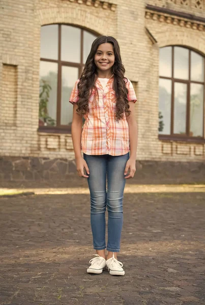 Kendin ol, herhangi bir şey ol. Mutlu çocuk dışarıda avluda duruyor. Çocuk kızın güzel görünüşü. Kuaför salonu. Çocuk bakımı ve çocukluk. Sıradan bir tarz. Moda sokak kıyafetleri. Yaz tatili. Çocuk Günü