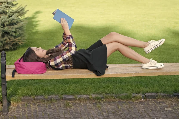 Leer es divertido. Niño feliz leer libro acostado en el banco del parque. Biblioteca escolar. Imaginación y fantasía. Educación de alfabetización. De vuelta a los útiles escolares. Actividades extraescolares. Leer nunca es aburrido —  Fotos de Stock