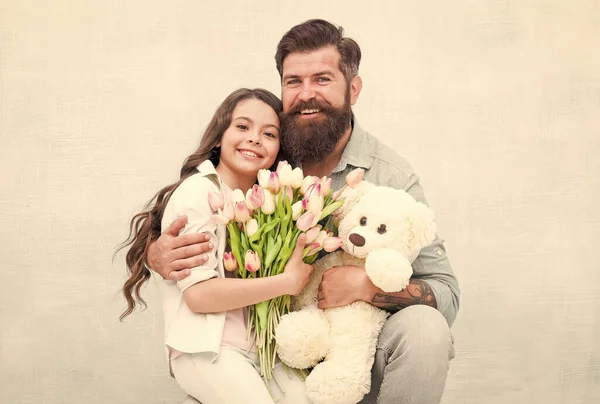 Estamos celebrando. La familia feliz celebra la fiesta juntos. Niño pequeño y barbudo disfrutan celebrando. Hija y padre sostienen flores y juguetes. Dar regalos. Celebración festiva. Feliz celebración. — Foto de Stock