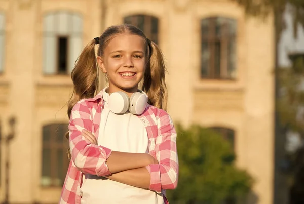 Mała dziewczynka casual stylu outdoor. Wiosenne wakacje właśnie się zaczęły. jej ulubiona letnia playlista. dziecko słucha muzyki. Uśmiechnięty dzieciak słuchający audiobooka. szczęśliwa uczennica nosi słuchawki. liceum. — Zdjęcie stockowe