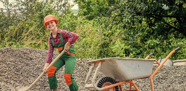 Chica con carretilla de escombros. niño trabajando en la obra. adolescente chica saca escombros de carretilla. niño con pala cargando piedras trituradas. Colocación de la fundación, proyecto de construcción — Foto de Stock