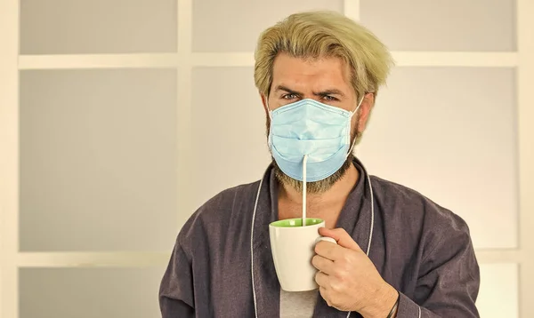 Bedek mond en neus met masker en zorg ervoor dat er geen gaten tussen gezicht en masker. Helemaal beschermd. Het dragen van masker beschermt tegen het coronavirus. Een gemaskerde man drinkt thee met stro. Serieus over hygiëne — Stockfoto