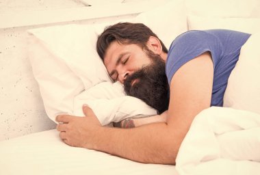 Gömlekli, yakışıklı, olgun bir adam yatakta uyuyor, sağlıklı bir uyku çekiyor.