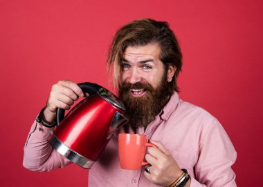 Hayattaki modern teknoloji. Sakallı hippi ev aletleri kullanır. Mutfak konsepti Bıyıklı vahşi yakışıklı adam çay içiyor. Olgun koca elektrikli su ısıtıcısı tutar. Şaşırma hissi