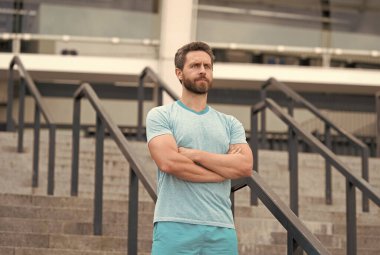 Yakışıklı sakallı adam kendine güvenerek ayakta duruyor. Formda ve sağlıklı kalmak. İyi bir spor şekli var. O her zaman formdadır. Ciddi sakallı adam ellerini çapraz yaptı. Kendine güvenen ve başarılı