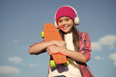 Ayaklarının altında biraz daha plastik var. Mavi gökyüzünde mutlu bir patenci. Bozuk para taşıyan küçük bir çocuk. Bozuk para kaykayına binmek. Hız ve denge. Yaz tatili ve tatiller. Yeni başlayanlar için bozuk para tahtası