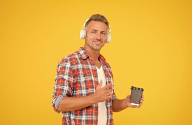 Güne başlamak için bundan bir fincan iç. Mutlu adam kahve bardağını işaret ediyor. Sabah alışkanlıkları. Müzik eğlenceli. Modern yaşam tarzı. Sıradan bir tarz. Tüm sabah boyunca enerjin açık olacak.