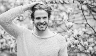 Hippi çiçek aromasının tadını çıkarır. İlkbahar konsepti. Tıraşsız bir adam manolya çiçeği koklar. Erkek çiçekli arka plan çözüldü. Bahar güzeli. Bahar sezonu. Botanik ve doğa. Mutlu bahar konsepti