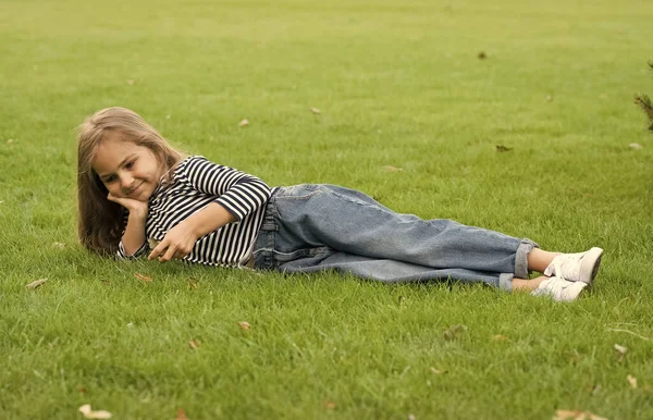 Schattig klein kind dragen casual mode stijl liggend op groen gras natuurlijk landschap, zomer — Stockfoto