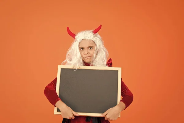 Bambino infelice indossare corna diavolo e parrucca capelli bianchi tenendo lavagna scuola per la pubblicità di Halloween, felice Halloween — Foto Stock
