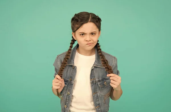 Kijk naar ontevredenheid. Ongelukkig meisje met gevlochten kapsel. Schoonheid van een klein kind. Een casual fashion look. Trendy stijl. Kinderkleding. Kapsalon. Update uw look — Stockfoto