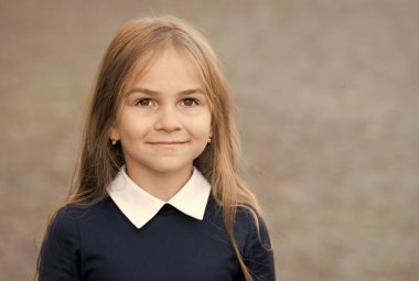 Uzun saçlı sevimli küçük bir çocuk okul üniforması giyiyor açık havada, kreşte, fotokopi odasında.