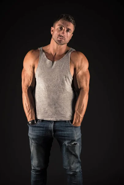 Сильный спортсмен показывает пригодные мускулистые руки бицепсы трицепсы мышцы носить повседневную майку с джинсами черный фон, спорт — стоковое фото