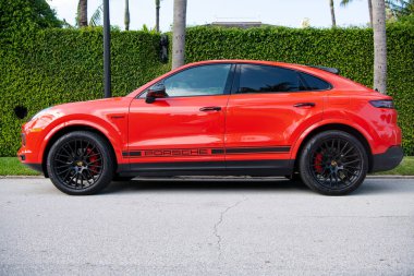 Palm Beach, Florida USA - March 21, 2021: orange Porsche Cayenne Coupe. side view.