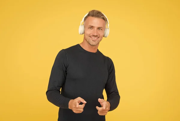 Handsome happy male with nice smile advises high quality headset being in good mood while listening music online, dj — Stock Photo, Image
